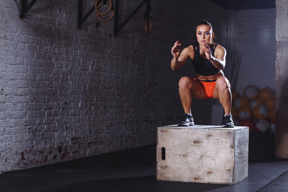 fit woman doing box jump exercise. Muscular woman doing box jumps at gym